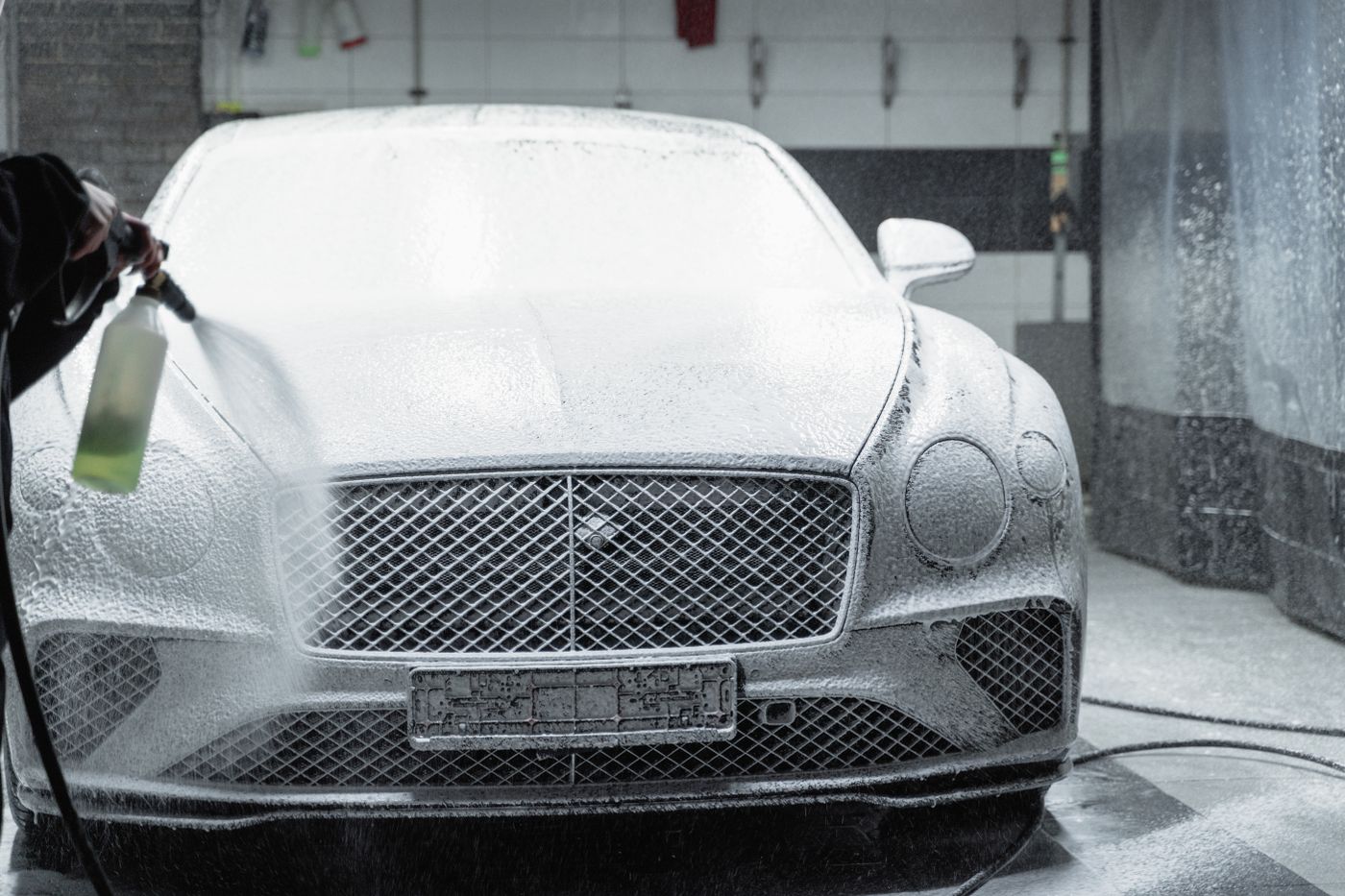 The foam-covered front end of a luxury car mid-wash