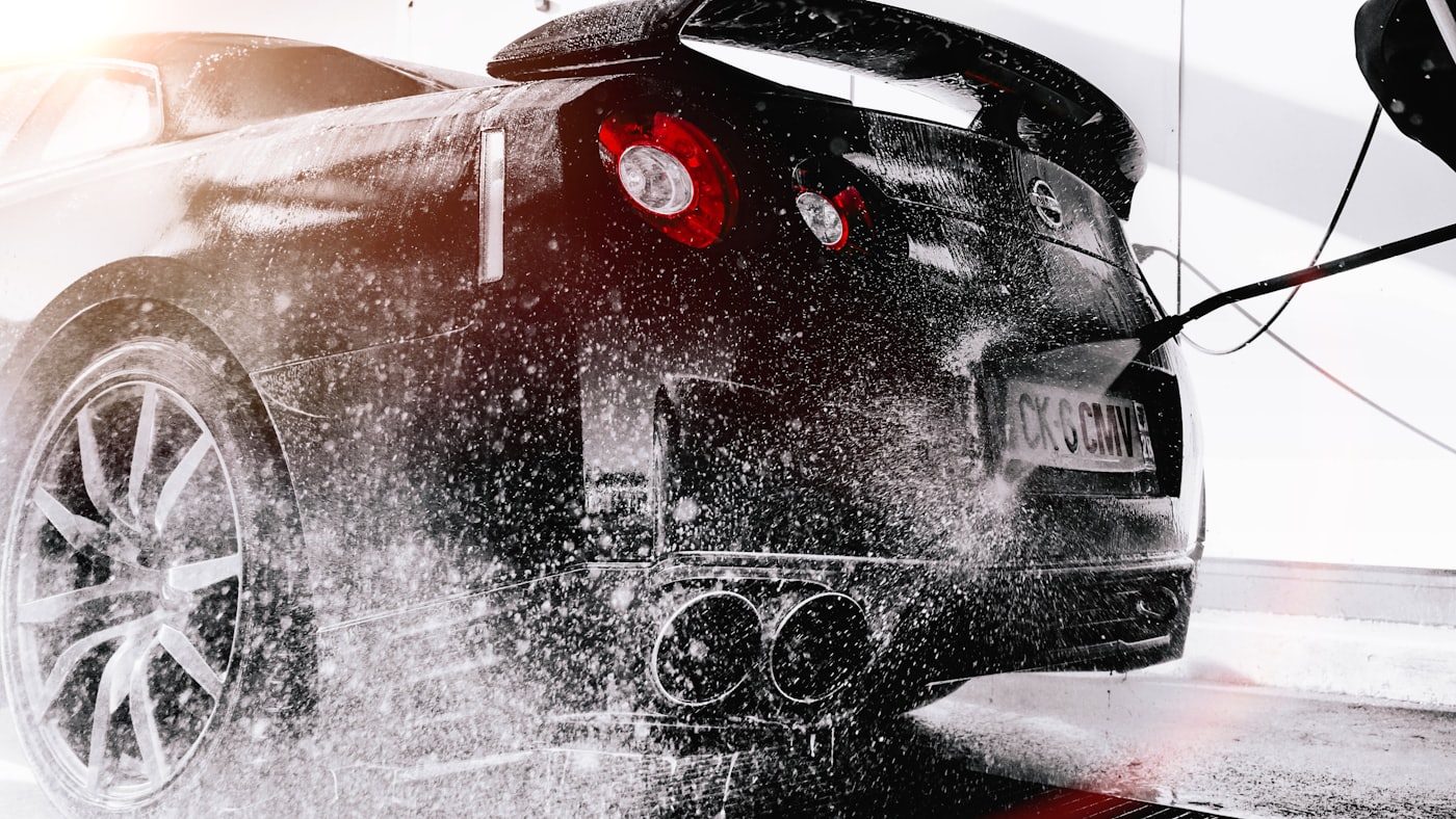 A black sports car blanketed in thick white foam during a DnA exterior detail