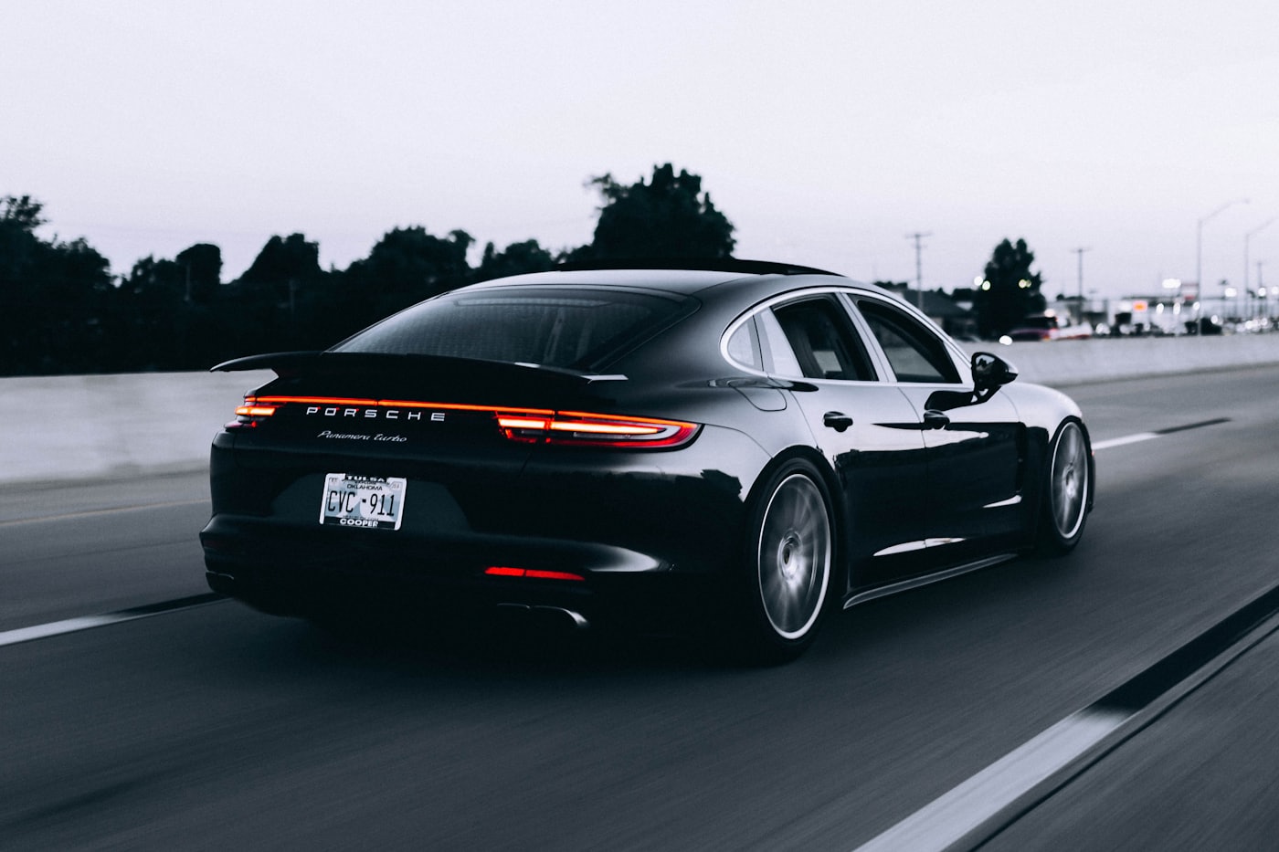 The gleaming rear of a black Porsche on the road at dusk after a DnA detail